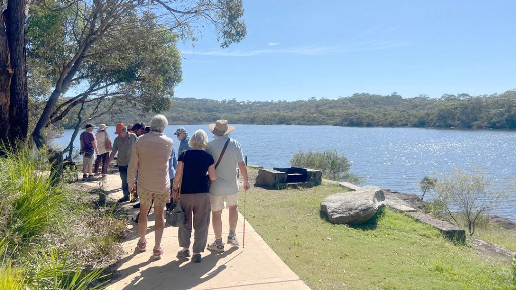 People walking along the bank of Manly dam on a sunny day