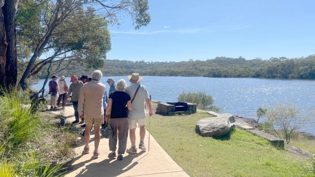 People walking along the bank of Manly dam on a sunny day